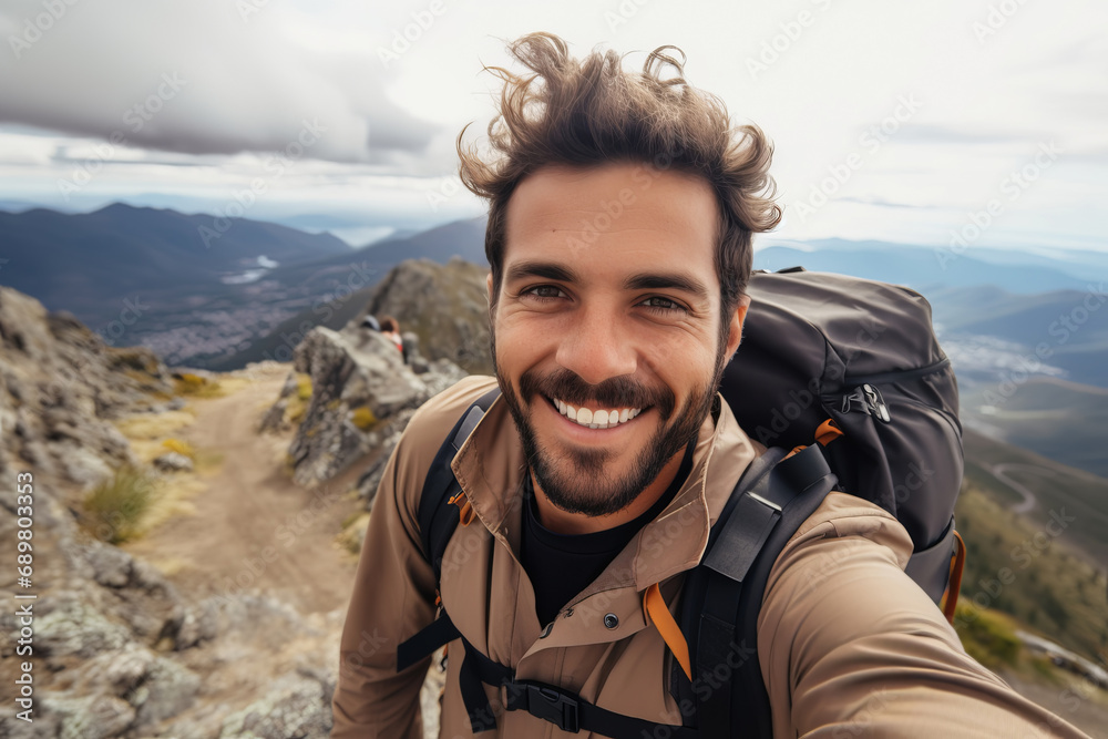 Happy hiker man taking selfie portrait on the top of mountain
