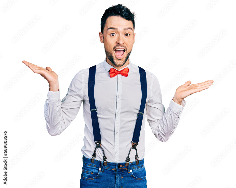 Hispanic man with beard wearing hipster look with bow tie and suspenders celebrating crazy and amazed for success with arms raised and open eyes screaming excited. winner concept Hispanic man with beard wearing hipster look with bow tie and suspenders celebrating crazy and amazed for success with arms raised and open eyes screaming excited. winner concept