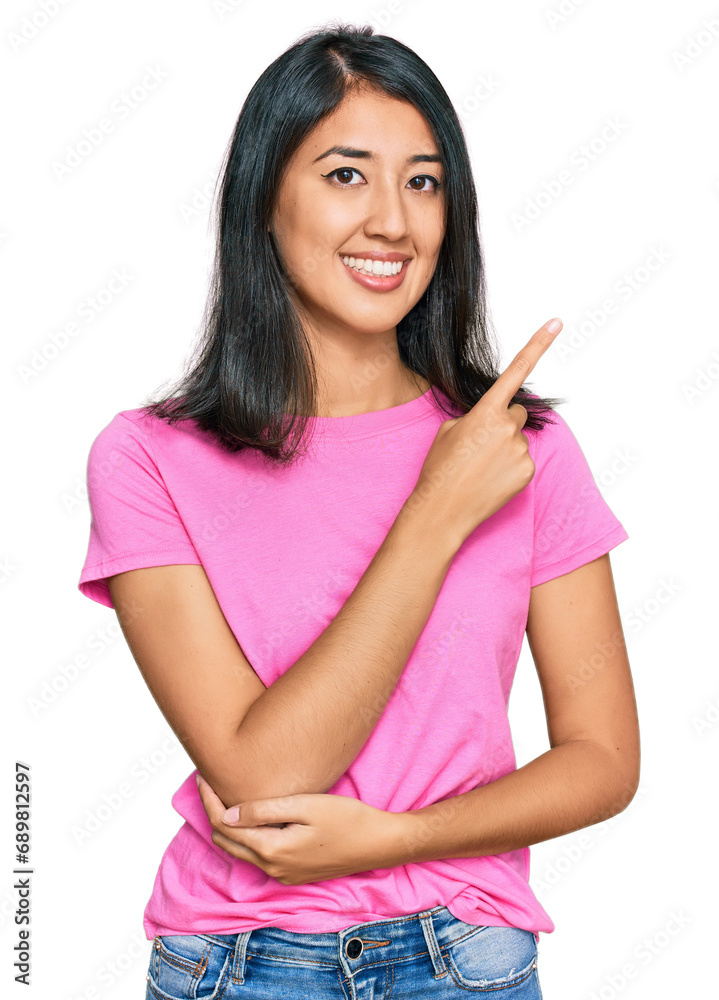 Beautiful asian young woman wearing casual pink t shirt with a big smile on face, pointing with hand and finger to the side looking at the camera. Beautiful asian young woman wearing casual pink t shirt with a big smile on face, pointing with hand and finger to the side looking at the camera.