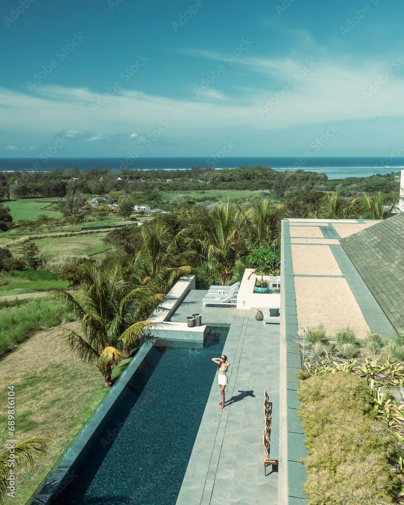 Aerial view of a woman relaxing on a terrace of a luxury resort with swimming pool, Bel Ombre, Savanne, Mauritius. Aerial view of a woman relaxing on a terrace of a luxury resort with swimming pool, Bel Ombre, Savanne, Mauritius.