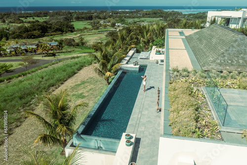 Aerial view of a woman relaxing on a terrace of a luxury resort with swimming pool, Bel Ombre, Savanne, Mauritius. photo