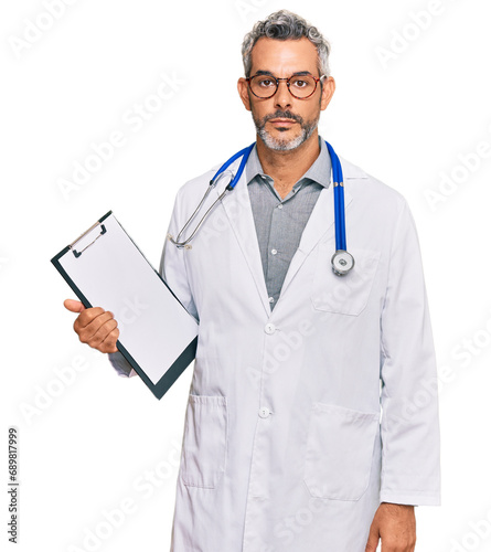 Middle age grey-haired man wearing doctor stethoscope holding clipboard thinking attitude and sober expression looking self confident photo