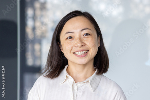 Portrait of young beautiful and successful Asian business woman  female employee smiling and looking at camera with crossed arms  financial woman satisfied with the results of her work achievement.