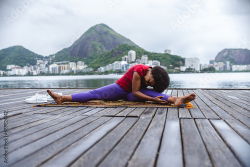 Mulher de meia idade se alongando, praticando ioga, sentada em um pier a beira da lagoa no Rio de Janeiro. photo