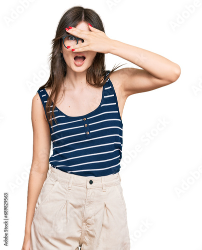 Young beautiful caucasian girl wearing casual clothes and glasses peeking in shock covering face and eyes with hand, looking through fingers with embarrassed expression.