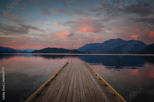 Sunset with Long Pier Leading Out into Water.  Harrison Lake, BC, Canada area is breathtaking with beautiful coves, beaches and islands, waterfalls, coniferous forests and snow-capped mountains. photo