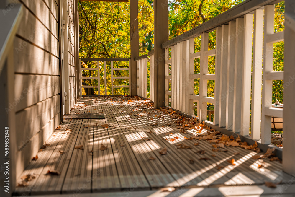 A cozy wooden house with autumn foliage and shadows - obrazy, fototapety, plakaty 