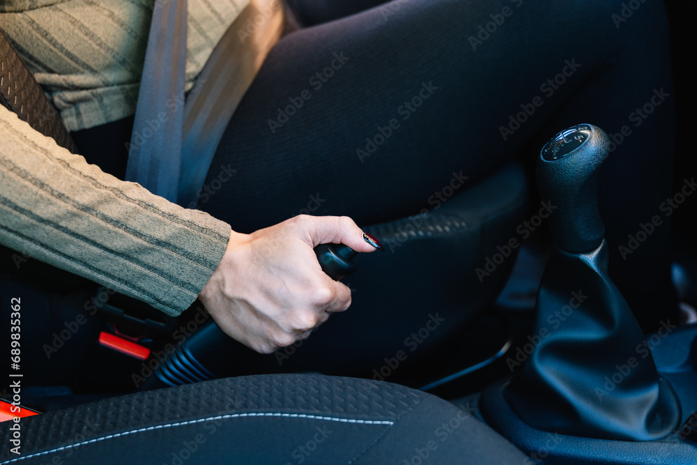 Close-up of a young woman driver's hand using the handbrake of her car. Driving concept Close-up of a young woman driver's hand using the handbrake of her car. Driving concept