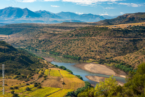 A river runs through a valley in rural Lesotho, with farms on the banks and mountains on the horizon