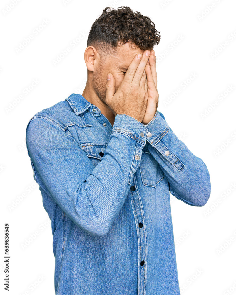 Young hispanic man wearing casual denim jacket with sad expression covering face with hands while crying. depression concept. Young hispanic man wearing casual denim jacket with sad expression covering face with hands while crying. depression concept.