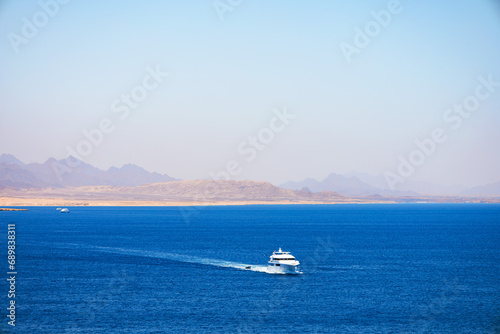 White boats on blue color of Red Sea with sandy and rocky coast in the background. Popular place of tourists. Ras Muhammad in Egypt at the southern extreme of the Sinai Peninsula. Travel concept © Avalepsap