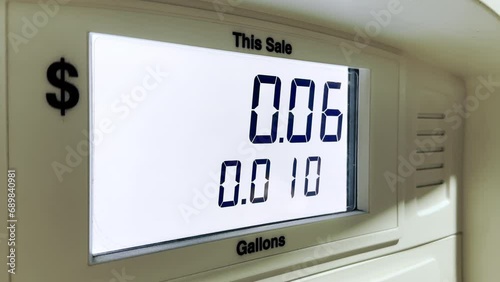 The screen of the fuel dispenser shows numbers indicating the quantity and cost of fuel being filled into the driver's car. The screen is illuminated with white light. photo