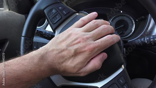 Angry driver honking the car horn in traffic, closeup of hand pushing the steering wheel honk photo
