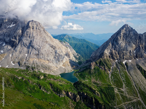 Aerial view of Volaia Lake  Wolayersee  in the border of Italy and Austria with Coglians mountain in the background. Cloudy day with some sun opening. Vibrant colors. Beautiful destinations for hikers