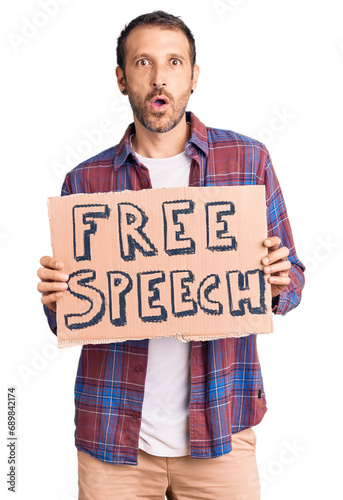 Young handsome man holding free speech banner scared and amazed with open mouth for surprise, disbelief face