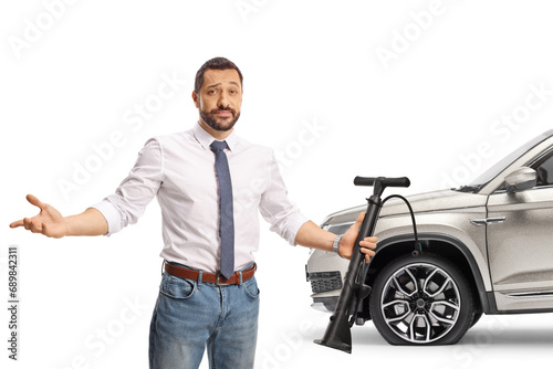 Man holding a manual tire pump in front of a car with flat tire photo