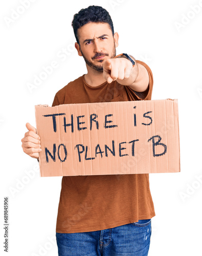 Young hispanic man holding there is no planet b banner pointing with finger to the camera and to you, confident gesture looking serious © Krakenimages.com