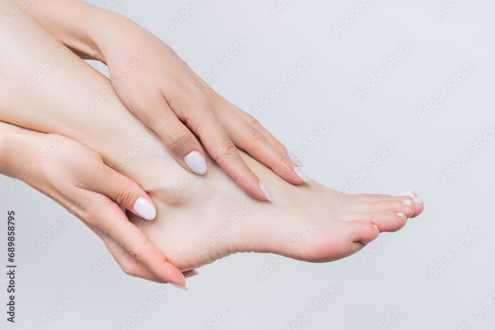 close-up woman gently touching her foot with both hands. Foot care. Beauty and hygiene. Isolated on a white background close-up woman gently touching her foot with both hands. Foot care. Beauty and hygiene. Isolated on a white background