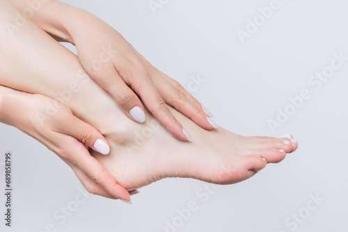 close-up woman gently touching her foot with both hands. Foot care. Beauty and hygiene. Isolated on a white background