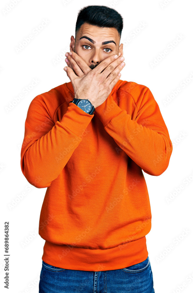Young hispanic man with beard wearing casual orange sweater shocked covering mouth with hands for mistake. secret concept. Young hispanic man with beard wearing casual orange sweater shocked covering mouth with hands for mistake. secret concept.