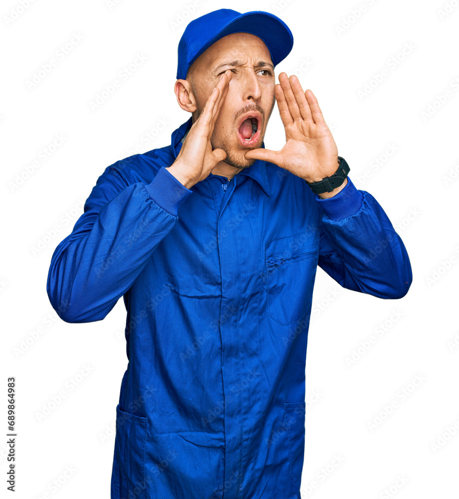 Bald man with beard wearing builder jumpsuit uniform shouting angry out loud with hands over mouth Bald man with beard wearing builder jumpsuit uniform shouting angry out loud with hands over mouth