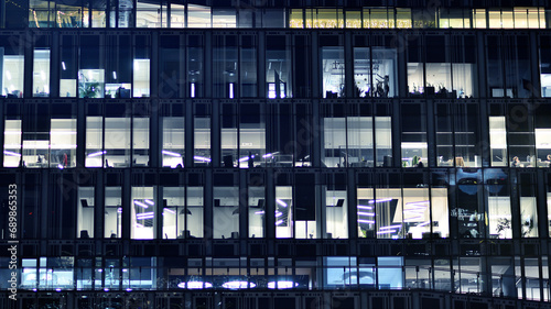 Fragment of the glass facade of a modern corporate building at night. Modern glass office in city. 