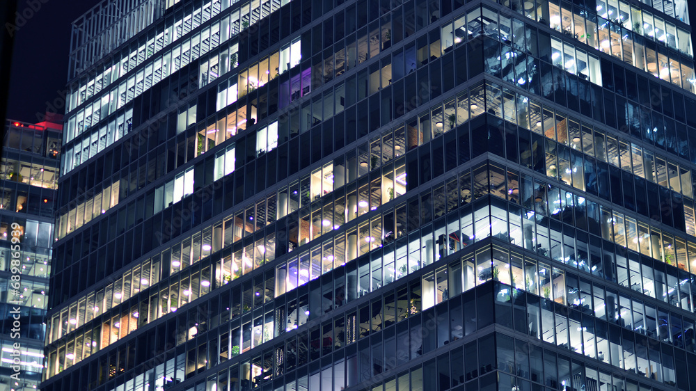 Fragment of the glass facade of a modern corporate building at night. Modern glass office in city. Fragment of the glass facade of a modern corporate building at night. Modern glass office in city.