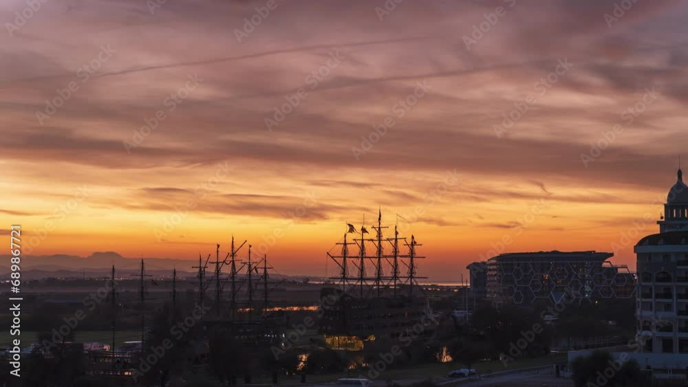 Fiery Rising Sun gradually paints the swiftly moving clouds with vibrant colors in the sky. Dock with sailing ships at sea. Time-lapse. Fiery Rising Sun gradually paints the swiftly moving clouds with vibrant colors in the sky. Dock with sailing ships at sea. Time-lapse.