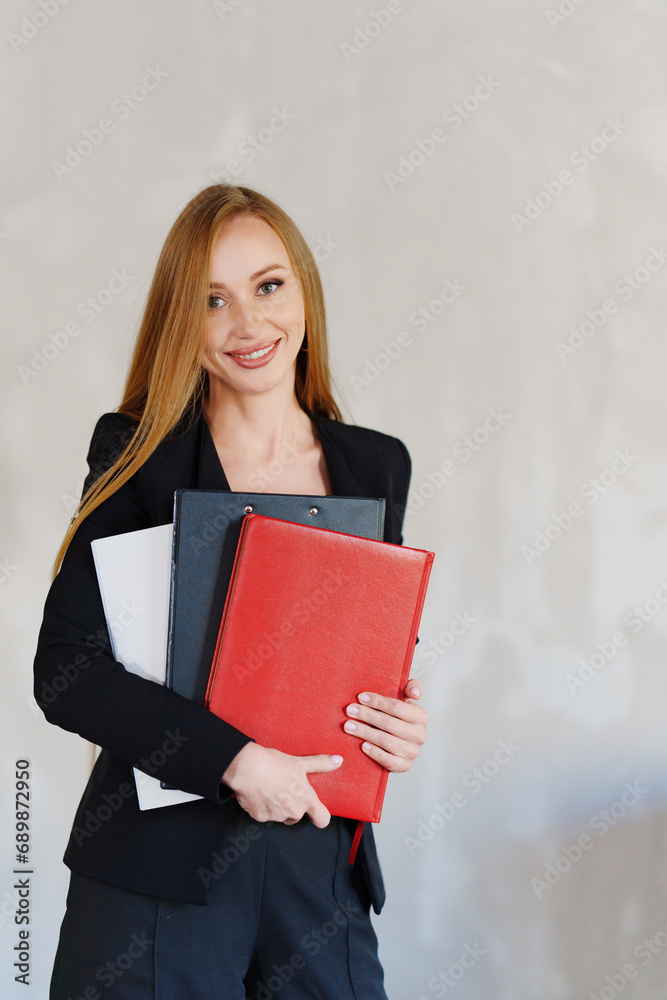Business redhead womanin a black business suit with folders of documents. Business redhead womanin a black business suit with folders of documents.