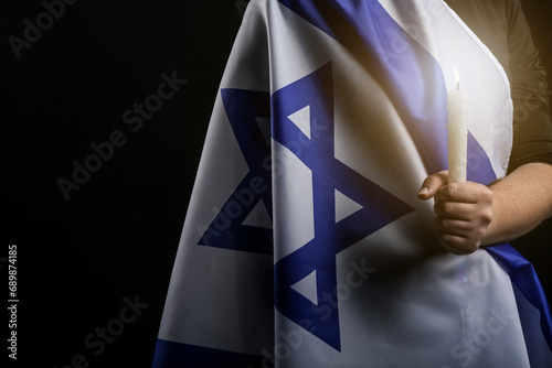 Jewish man with flag of Israel and burning candle on dark background. International Holocaust Remembrance Day photo