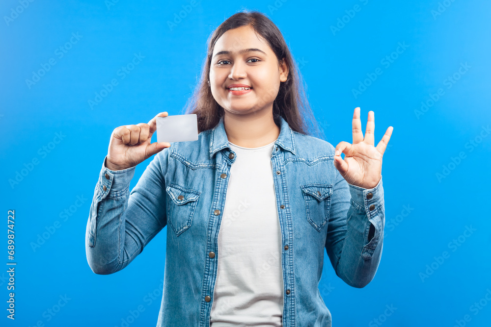 Asian women smiling with credit card and doing okay sign over blue background