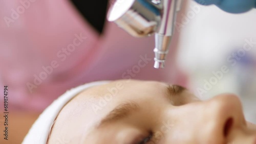 Beautician cosmetologist makes a procedure for skin face non-injection oxygen mesotherapy with air pressure with device. Hardware cosmetology in clinic salon for client.	 photo