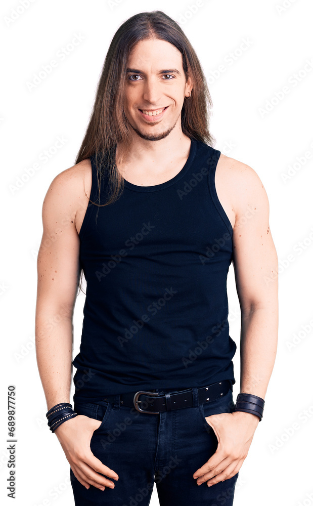 Fototapeta premium Young adult man with long hair wearing goth style with black clothes with a happy and cool smile on face. lucky person.
