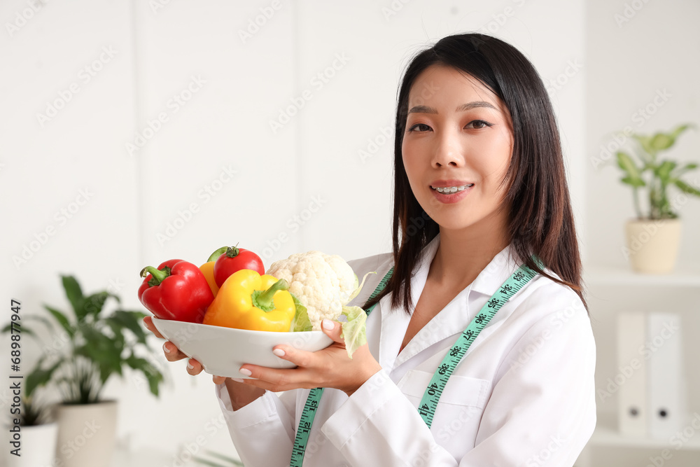 Female Asian nutritionist with healthy food in office