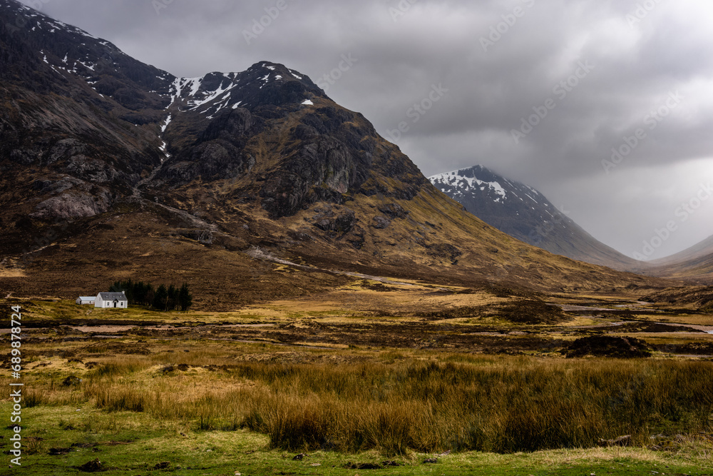 Beautiful vista with the white house and waterfalls near Three Sisters Mountains in Glencoe, the Scottish Highlands, Scotland UK