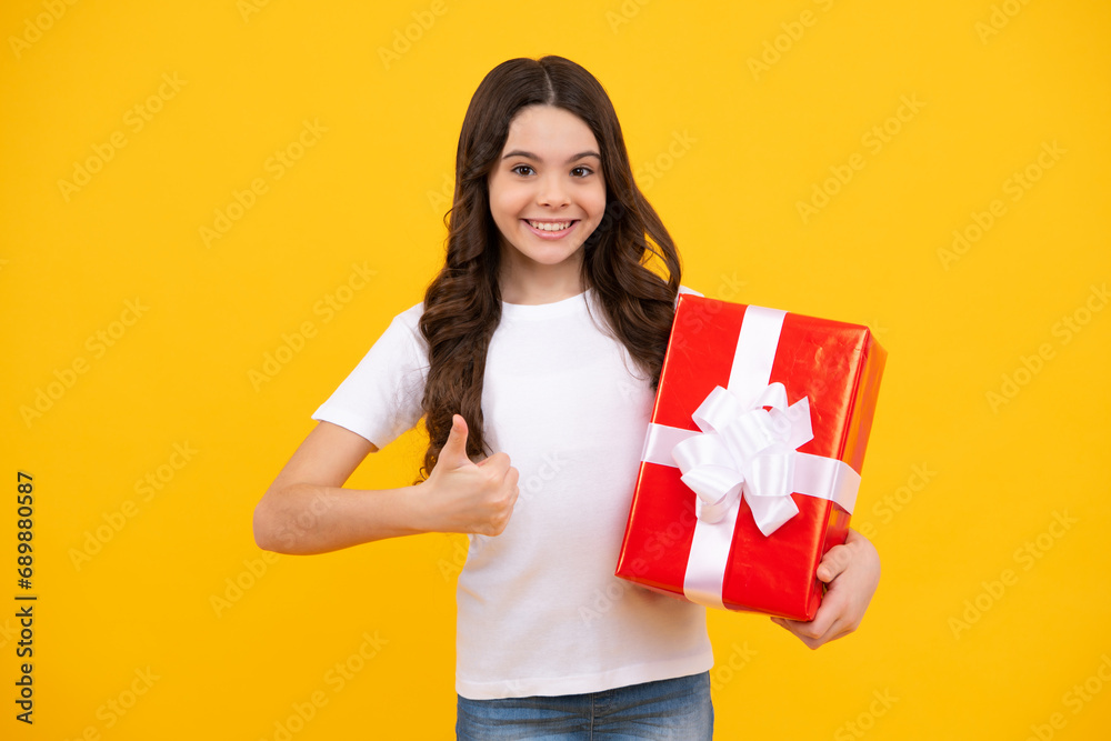 Fototapeta premium Happy teenager, positive and smiling emotions of teen girl. Child with gift present box on isolated studio background. Gifting for kids birthday.