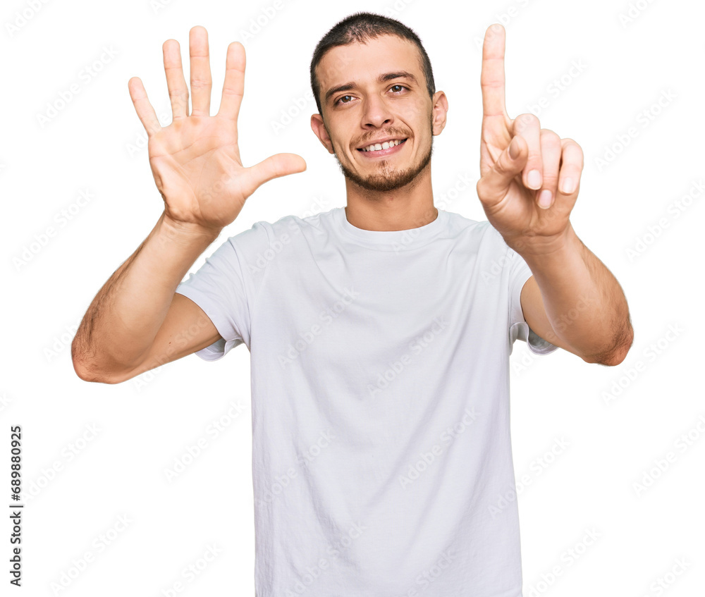 Hispanic young man wearing casual white t shirt showing and pointing up with fingers number six while smiling confident and happy. Hispanic young man wearing casual white t shirt showing and pointing up with fingers number six while smiling confident and happy.