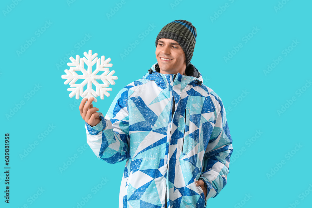 Young man in winter clothes with snowflake on color background Young man in winter clothes with snowflake on color background