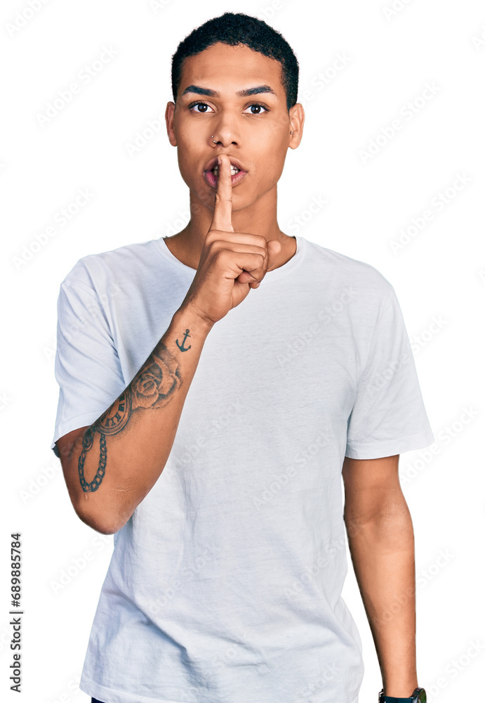Young hispanic man wearing casual white t shirt asking to be quiet with finger on lips. silence and secret concept. Young hispanic man wearing casual white t shirt asking to be quiet with finger on lips. silence and secret concept.