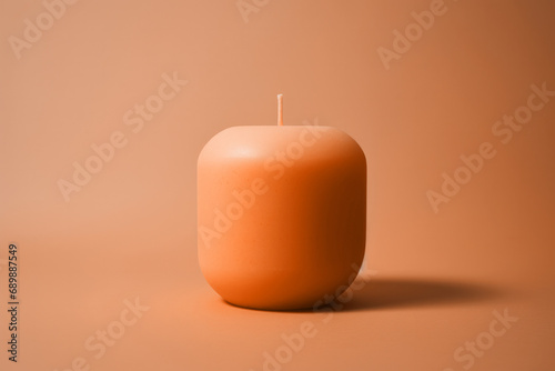 A simple unlit peach fuzz color candle on minimal background. Modern trendy tone hue shade photo