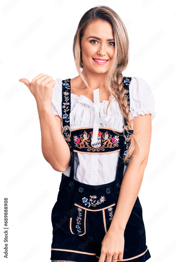 Φωτογραφία Young beautiful blonde woman wearing oktoberfest dress smiling with happy face looking and pointing to the side with thumb up