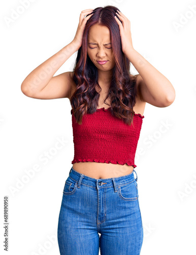 Young beautiful chinese girl wearing casual clothes suffering from headache desperate and stressed because pain and migraine. hands on head. © Krakenimages.com