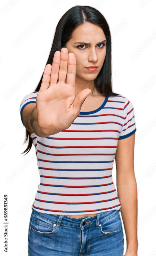 Young hispanic girl wearing casual striped t shirt doing stop sing with palm of the hand. warning expression with negative and serious gesture on the face. Young hispanic girl wearing casual striped t shirt doing stop sing with palm of the hand. warning expression with negative and serious gesture on the face.