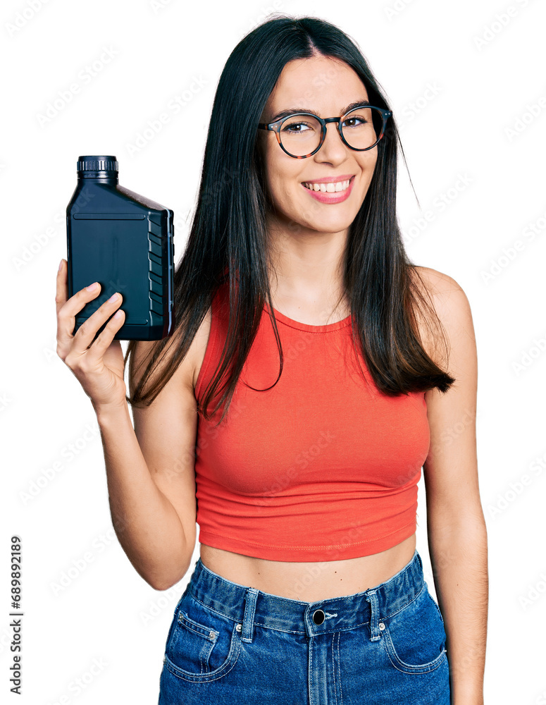 Young hispanic woman holding motor oil bottle looking positive and happy standing and smiling with a confident smile showing teeth Young hispanic woman holding motor oil bottle looking positive and happy standing and smiling with a confident smile showing teeth