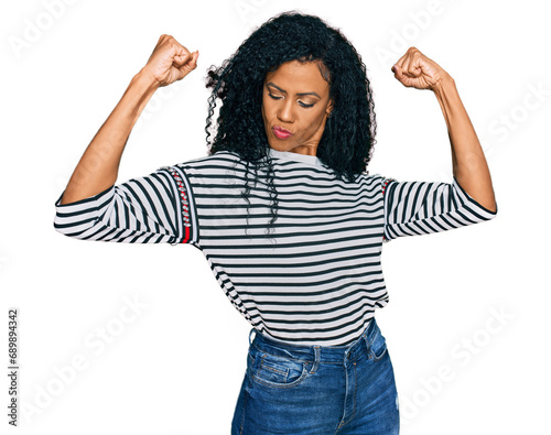 Middle age african american woman wearing casual clothes showing arms muscles smiling proud. fitness concept. © Krakenimages.com