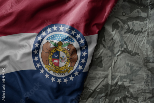 waving flag of missouri state on the old khaki texture background. military concept.