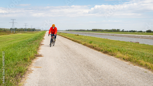 senior athletic man is riding a gravel touring bike - biking on a levee trail along Chain of Rocks Canal near Granite City in Illinois