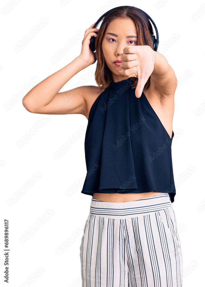 Φωτογραφία Young beautiful chinese girl listening to music using headphones with angry face