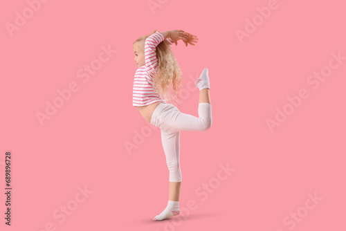 Cute little girl doing gymnastic exercises on pink background