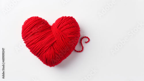 Coeur tricoté avec une pelote de laine de fil rouge. Amour, sentiment, tricot, couture. Pour conception et création graphique.  photo